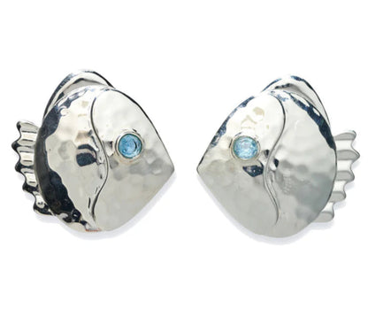 The Lizzie Fortunato Mikuni Stud Earrings are hammered silver, fish-shaped studs accented with blue semiprecious quartz eyes, shown on a white background.