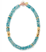 The Toga Beach Necklace by Lizzie Fortunato features cobalt blue recycled glass beads, gold cylindrical accents, a freshwater pearl, and a small gold tag at the clasp.