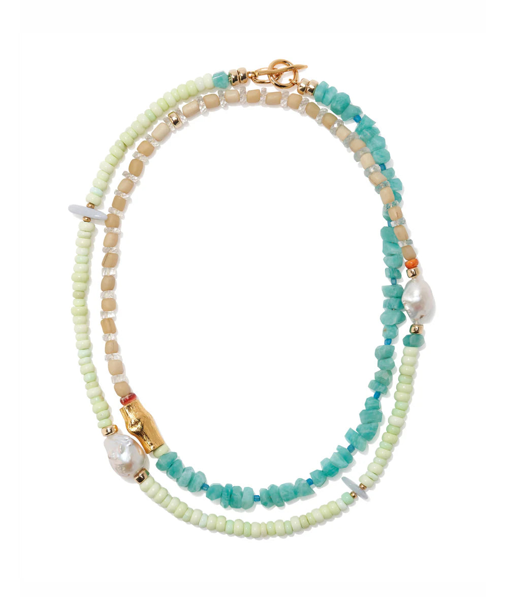 The Cabana Necklace by Lizzie Fortunato features turquoise stones, pale green and beige beads, gold accents, and two irregular pearls in a chic layered design.