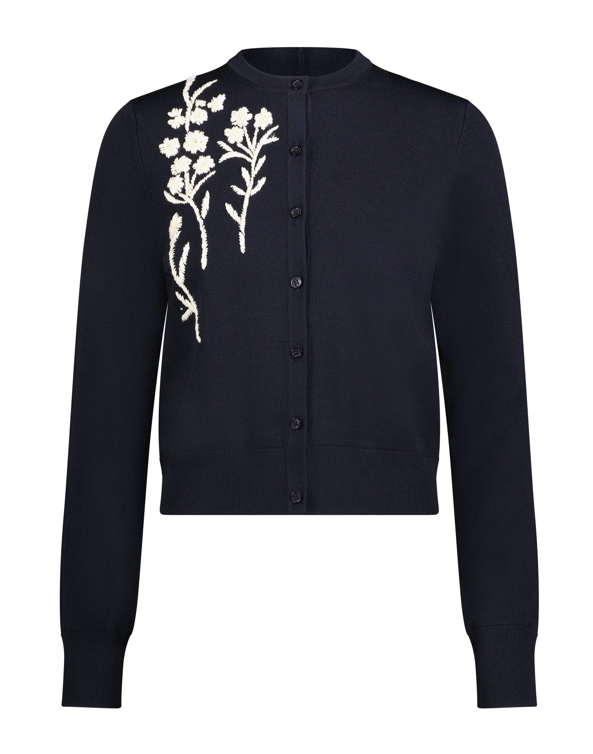 The Lela Rose Raffia Embroidered Knit Long Sleeve Cardigan features a navy blue knit fabric, button-up front, and white floral embroidery on the left shoulder and chest.