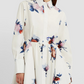 A person wearing the Erdem Long Sleeve Midi Shirt Dress, featuring a collared neckline and decorated with blue and pink rose bouquets.
