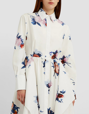 A person wearing the Erdem Long Sleeve Midi Shirt Dress, featuring a collared neckline and decorated with blue and pink rose bouquets.
