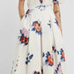 A person wearing the Erdem Painted Rose Bouquet Pleated Midi Skirt in a colorful floral print; only the body is visible, the face is not shown.