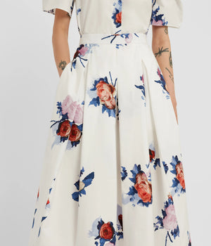 A person wearing the Erdem Painted Rose Bouquet Pleated Midi Skirt in a colorful floral print; only the body is visible, the face is not shown.