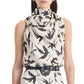 A woman wears the Altuzarra Sleary Top, a sleeveless silk piece with a high cowl neckline and black bird print, paired with a matching high-waisted skirt and black belt.