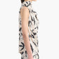 A woman stands in profile wearing the Altuzarra Sleary Top, a sleeveless, high-neck cream silk piece with a black floral print.