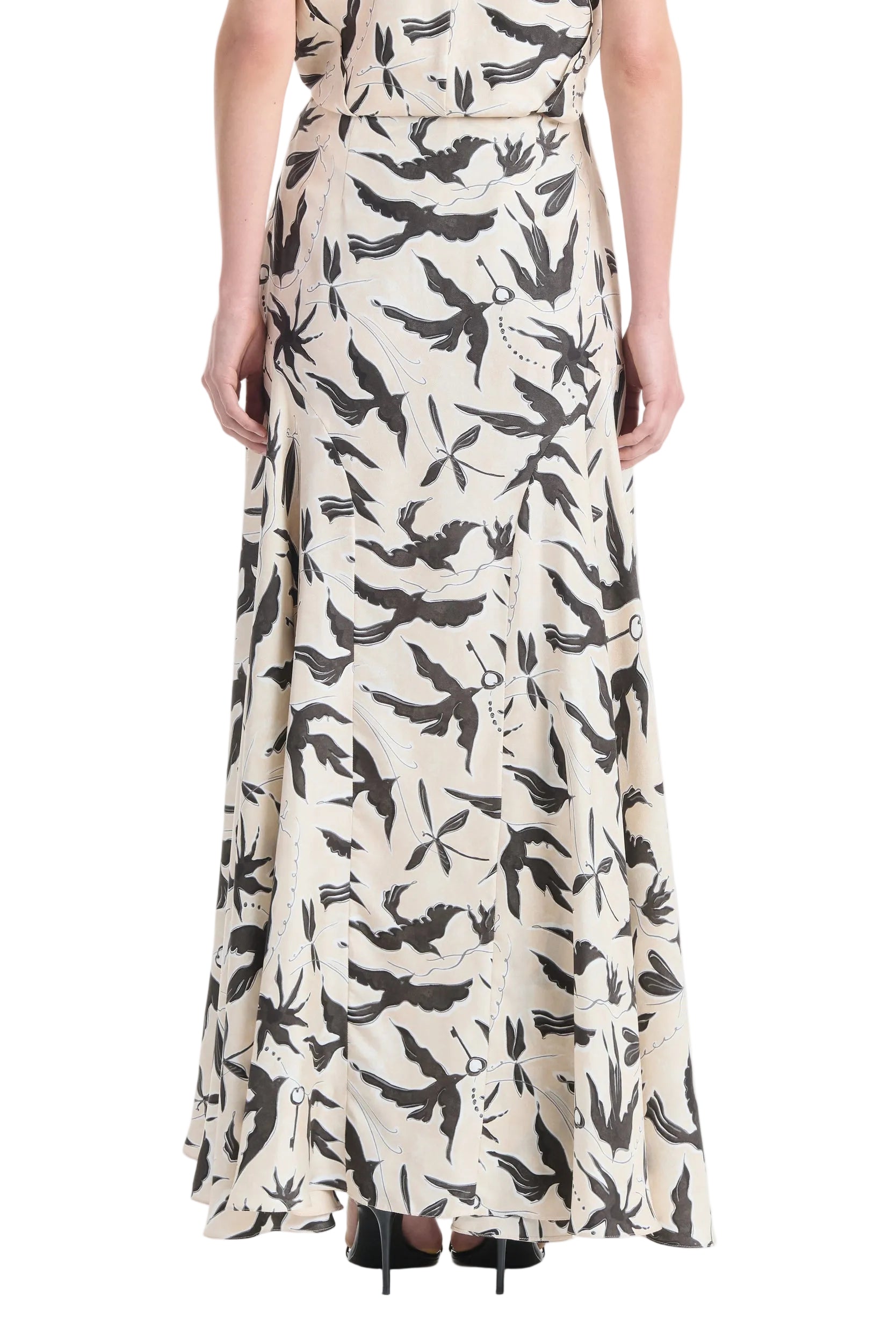 A person wearing the Altuzarra Elton Skirt, a long beige skirt featuring a black and gray abstract print and flared silhouette, is shown from the back against a white background.