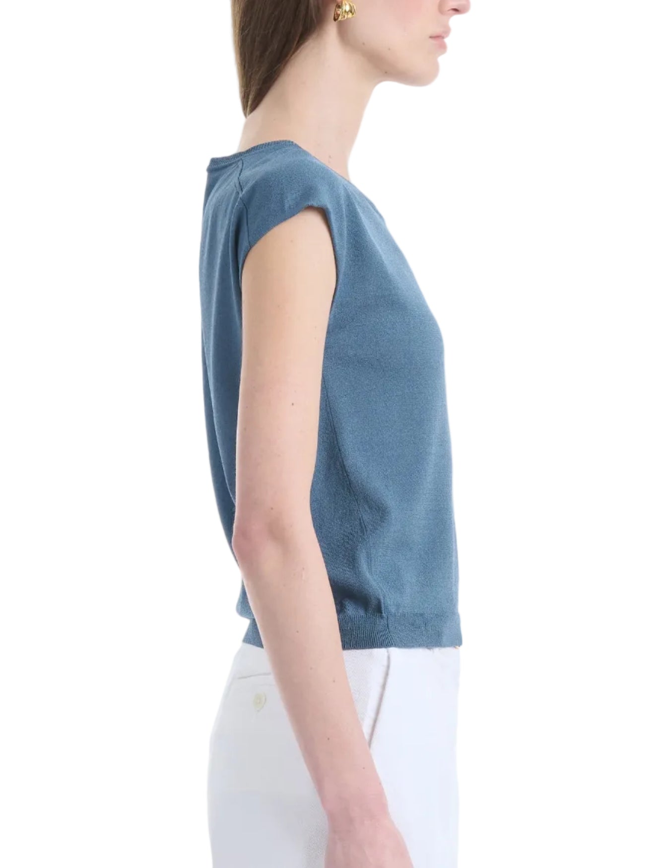 A woman in profile wears the Altuzarra Rinaldi Top, a blue gathered-shoulder style, paired with white pants against a plain background.