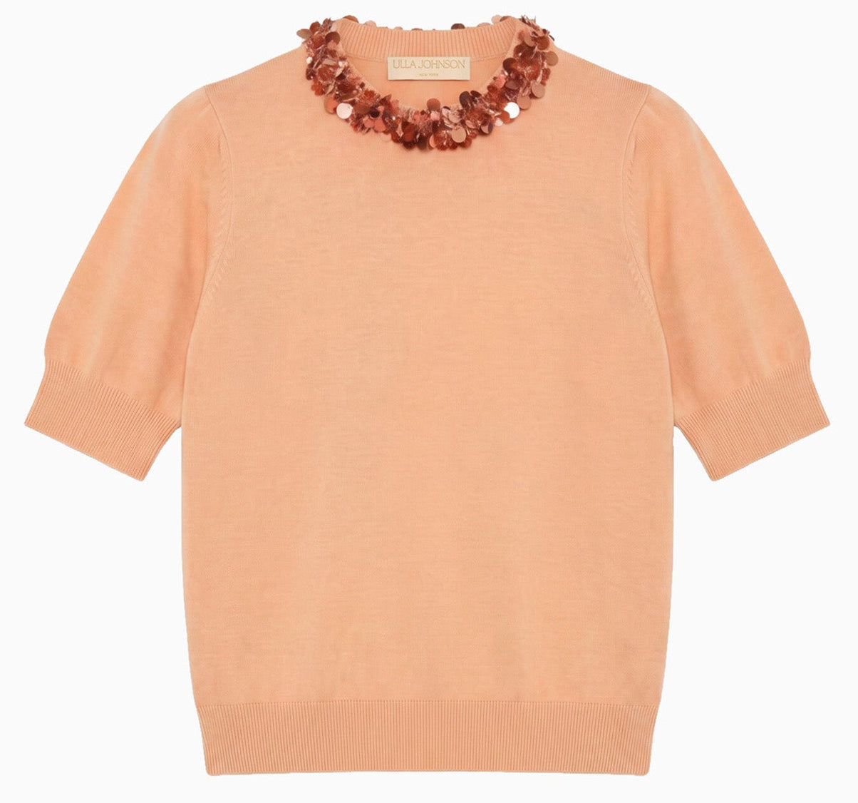The Jude Embellished Top by Ulla Johnson is a peach merino wool short-sleeve knit sweater with ribbed cuffs and hem, adorned with a decorative beaded necklace detail at the neckline.