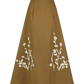 The Lela Rose Leather Floral Embroidered Rustic Skirt is a brown A-line midi with white floral embroidery near the hem, shown against a plain white background.