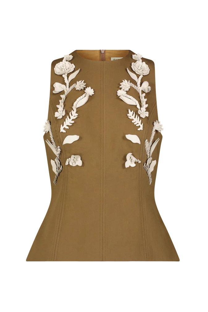 The Leather Floral Embroidered Rustic Top by Lela Rose is a sleeveless tan piece in stretch cotton, featuring a flared hem and white 3D floral appliqué for westernwear charm.