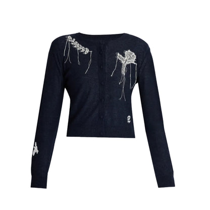The Fine Alpaca Blend Fitted Cardigan by Erdem is a navy long-sleeve button-up featuring white embroidery on the shoulder, chest, sleeve, and hem, inspired by Erdem’s Belle Époque Pre Fall 2026 collection.