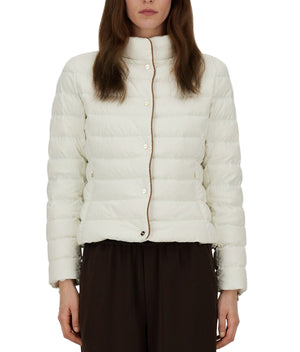 A person wears the Herno Arendelle Jacket—a white, quilted slim fit in super-matt polyester with brown trim—paired with dark pants, shown from the waist up.