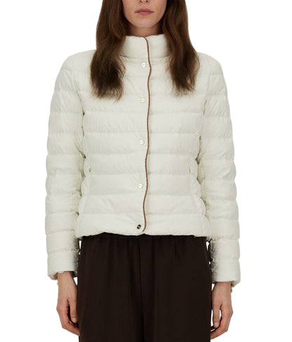 A person wears the Herno Arendelle Jacket—a white, quilted slim fit in super-matt polyester with brown trim—paired with dark pants, shown from the waist up.