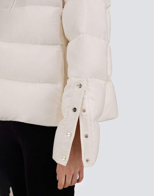 Close-up of a white Herno Cashmere Silk Jacket sleeve, featuring an eco-friendly, water-repellent quilted design with a side slit and snap button closures.