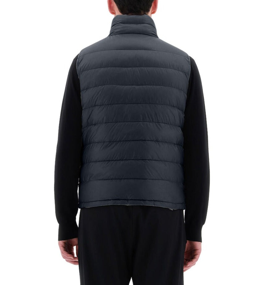 A person is wearing a Herno Men's Nylon Ultralight Reversible Vest, with their back to the camera against a white background, paired with black clothing.