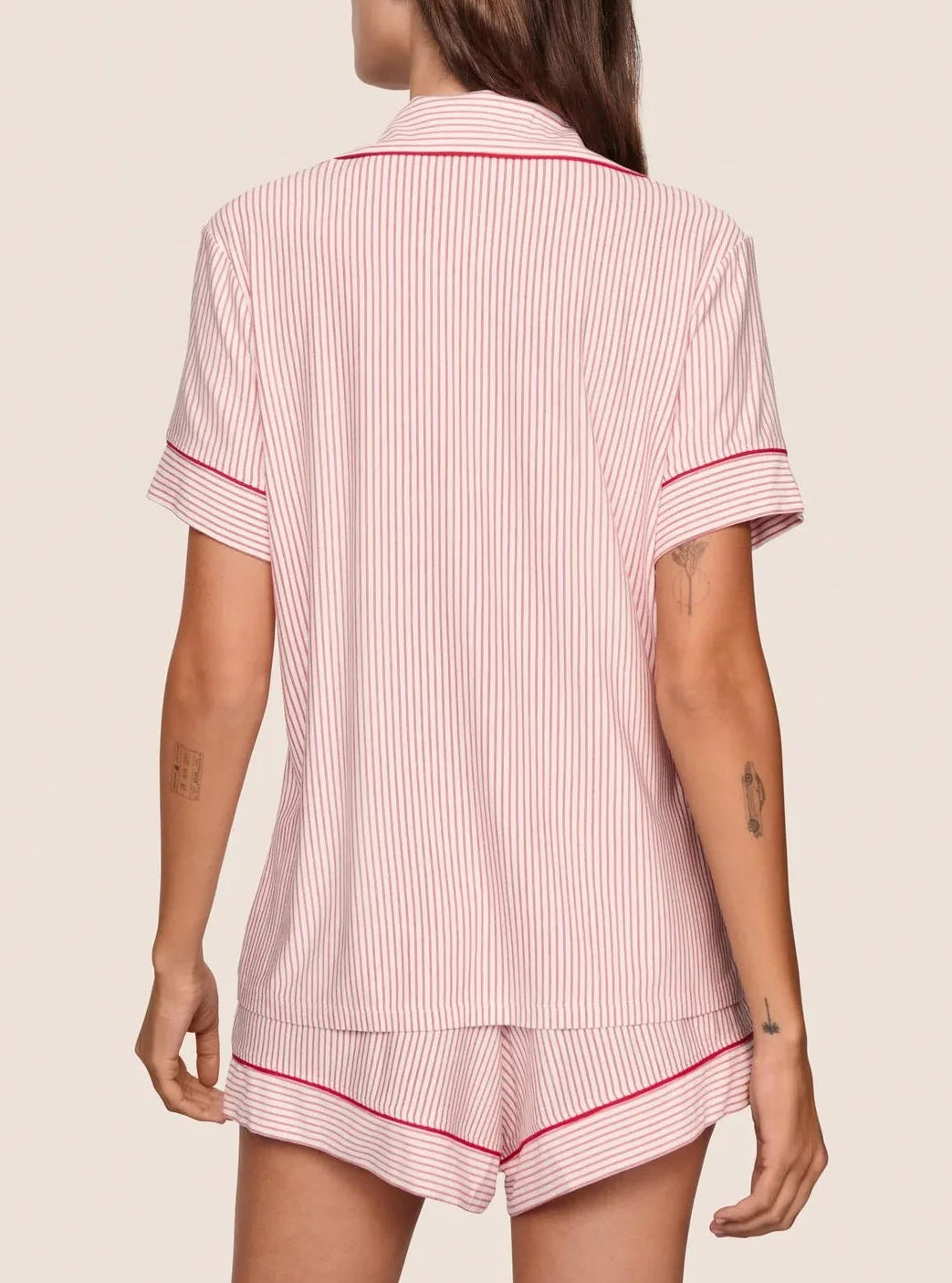 A person in the Eberjey Gisele Printed Stripe Relaxed Short PJ Set, featuring pink and white stripes with red trim, is shown from the back against a plain background. Made from buttery soft materials for ultimate comfort.