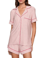 A woman wears the Eberjey Gisele Printed Stripe Relaxed Short PJ Set, a buttery soft, cozy sleepwear featuring red and white vertical stripes, red trim, short sleeves, button-up top, and matching shorts.