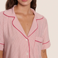 A person wears the Eberjey Gisele Printed Stripe Relaxed Short PJ Set—a pink and white pinstriped pajama top with red piping, buttons, and chest pocket—crafted for ultimate comfort.
