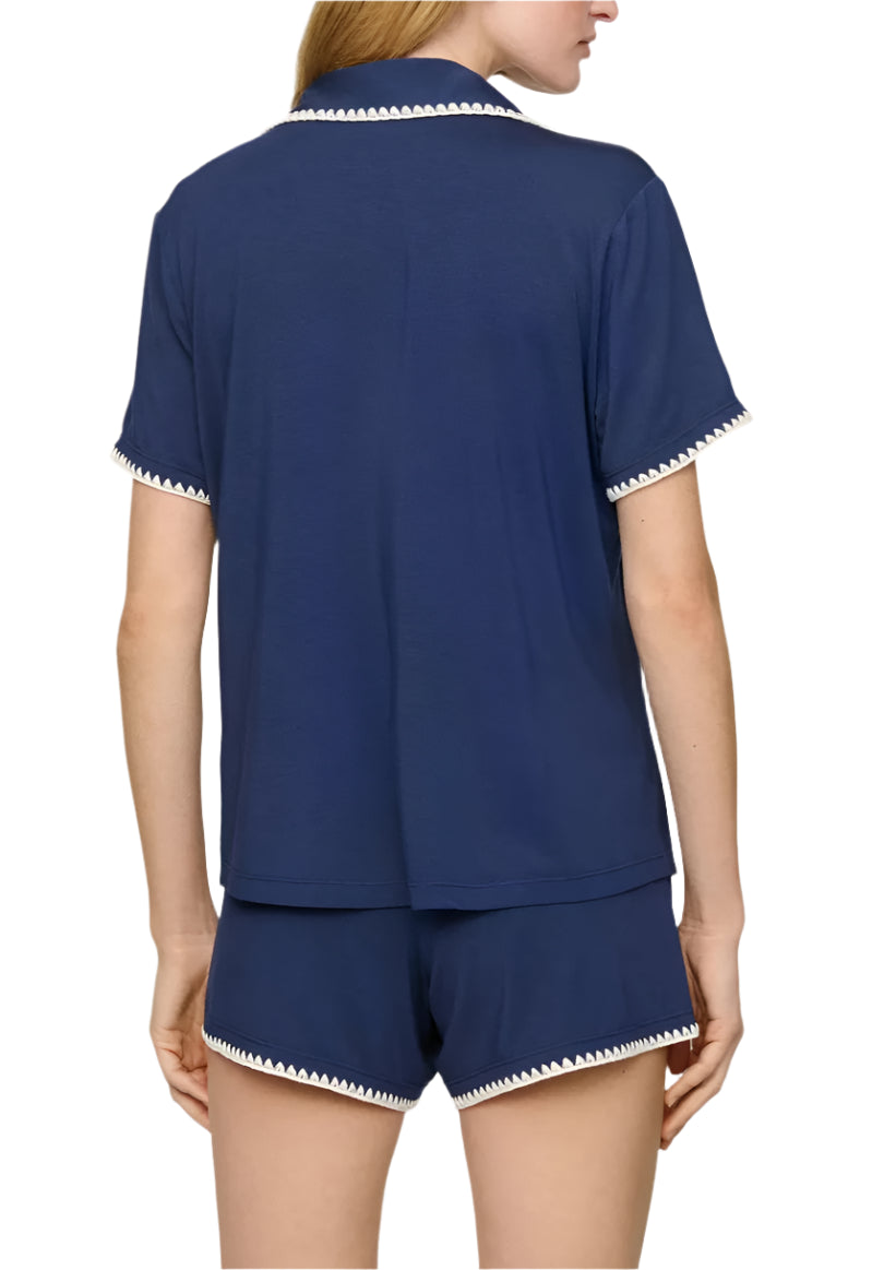 A person is shown from the back, wearing Eberjey's Frida Relaxed Short PJ Set in navy blue with white trim on the collar, sleeves, and boyfriend-fit shorts for a comfortable and relaxed look.