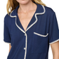 A woman wears the Eberjey Frida Relaxed Short PJ Set—featuring a navy, relaxed-fit short-sleeve top with white scalloped trim, chest pocket, and button-down front.