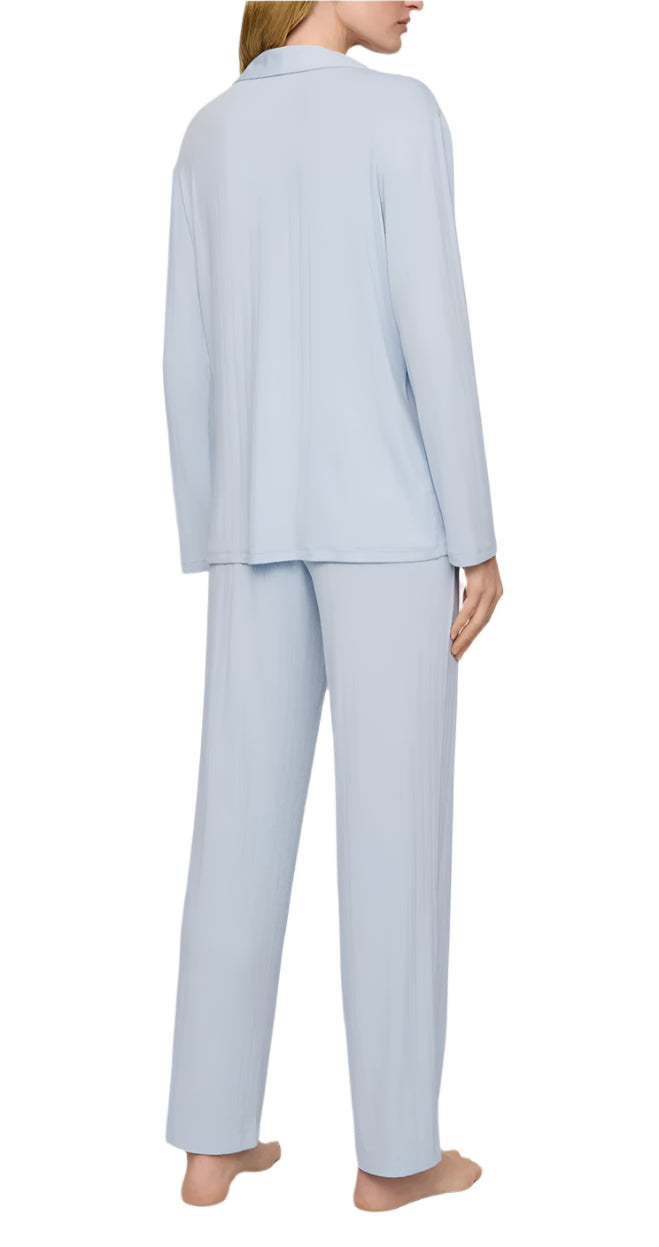A person is seen from the back wearing the Eberjey Gisele Rib Long PJ Set, a light blue sleep set featuring an elastic waistband and button-down top, barefoot.