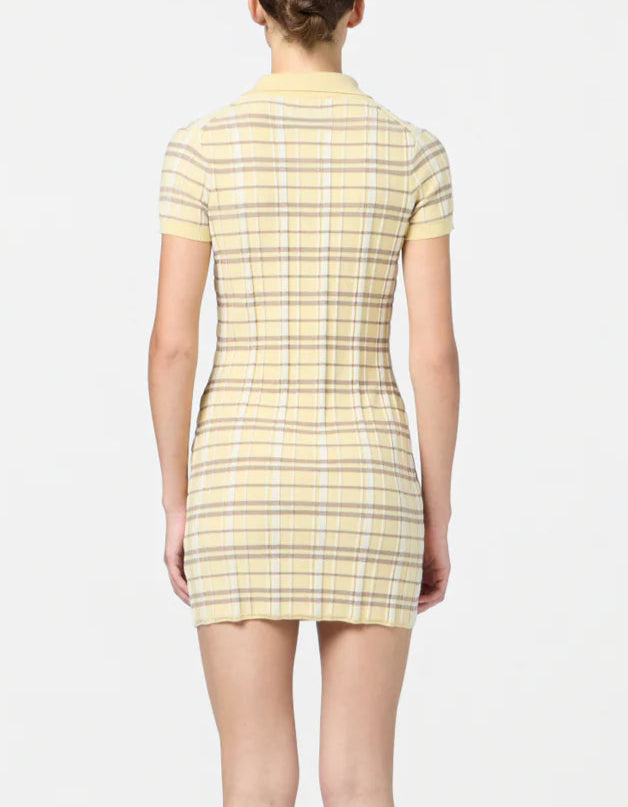A person is seen from the back wearing the Guest in Residence Plaid Polo Dress, a short-sleeved yellow plaid piece, made from a silk linen blend, standing against a plain white background.