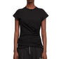A person wears the 3.1 Phillip Lim Draped SS T-Shirt, a fitted black mercerized cotton jersey with side ruching, paired with black tailored trousers featuring front zippers.