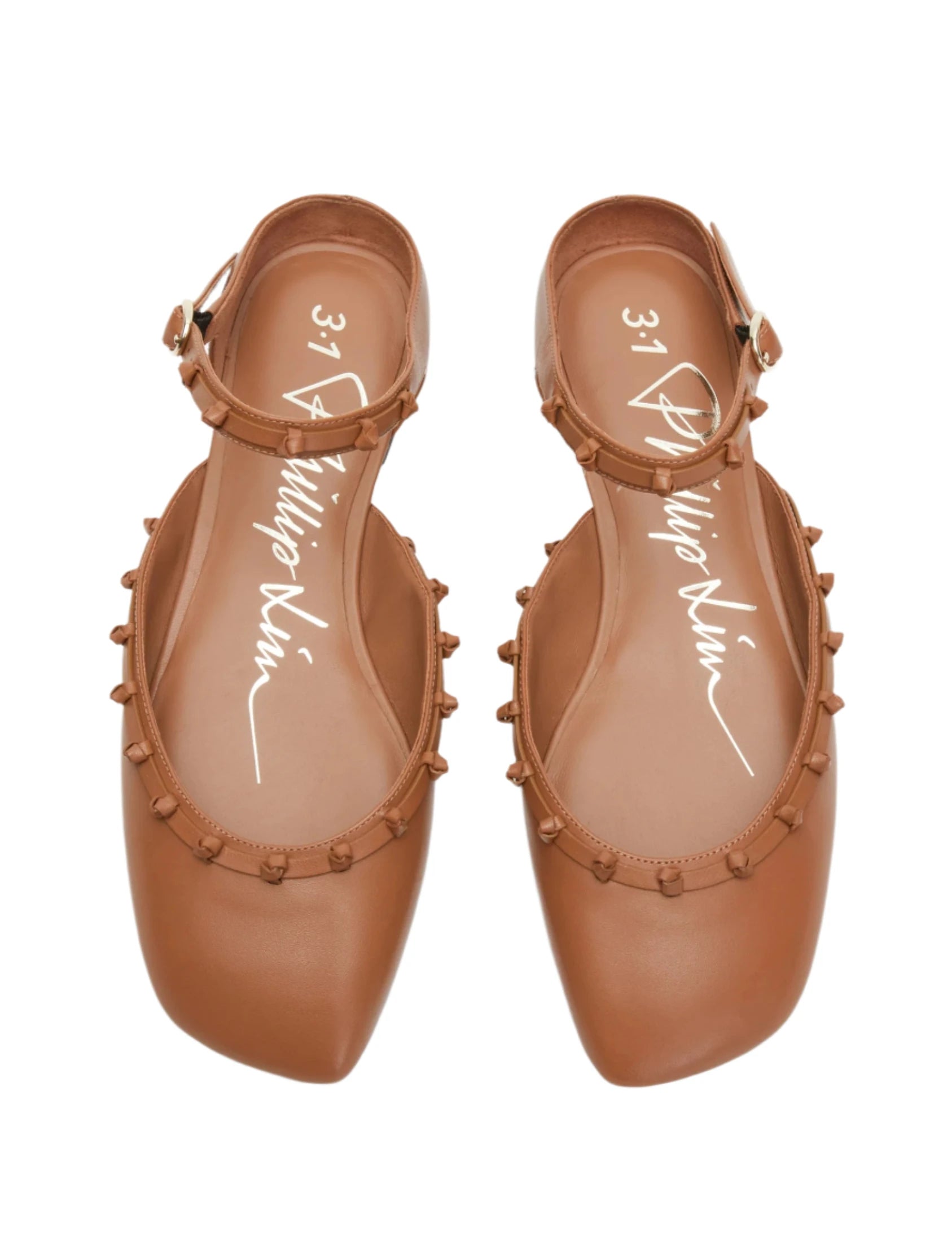 Introducing the 3.1 Phillip Lim ID Mary Jane Flat Leather Craft, a pair of brown leather flats from 3.1 Phillip Lim that features ankle straps and rounded embellishments along the edges. These stylish shoes are inspired by classic Mary Janes and boast intricate leather knots for added charm.