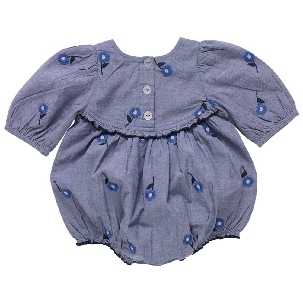 The Pink Chicken Baby Girls' Rowan Bubble is a blue romper with short puffed sleeves, back buttons for easy changes, a ruffle detail, and a charming blue floral pattern.