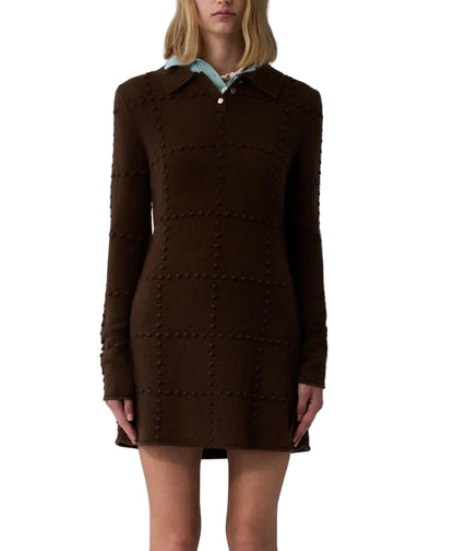 A woman wears the Guest in Residence Popcorn Polo Dress, a long-sleeve brown dress with a grid pattern, paired with a light blue collared shirt underneath.