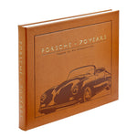 A brown hardcover book, “Porsche 70 Years: There is No Substitute” by Graphic Image, features an embossed Porsche outline and celebrates the brand’s rich automotive history.