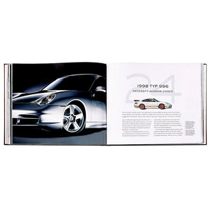 An open book, *Porsche 70 Years: There is No Substitute* by Graphic Image, displays a photo of a silver sports car and text about the 1998 Porsche 996, highlighting a piece of Porsche’s iconic automotive history.