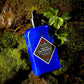 A blue bottle of Jack Black Double-Duty Face Moisturizer sits on green moss beside fresh parsley leaves.