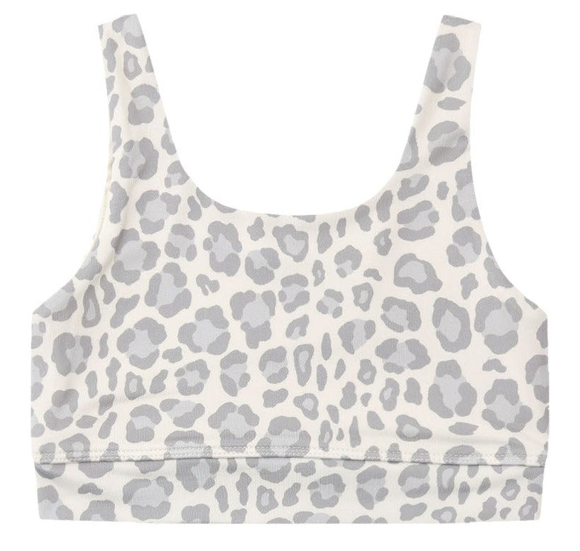 Rylee & Cru Girls’ Swift Sports Bra features a classic fit with a white scoop neck and light gray leopard print pattern, shown laid flat against a white background—perfect for everyday wear.