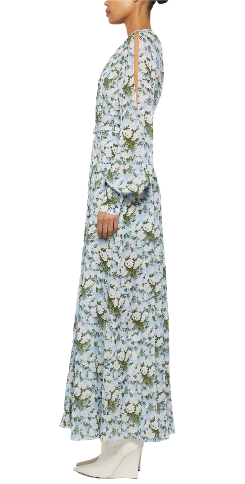 A person in side profile wears the Prabal Gurung Huma Maxi Dress—featuring a flattering fit, floral pattern, and shoulder cutouts—with white ankle boots against a white background.