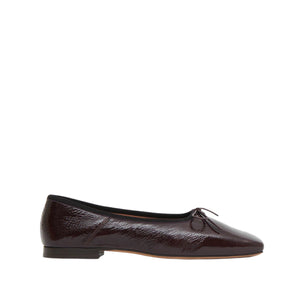 The Mansur Gavriel Square Toe Ballerina is a dark brown patent leather Mary Jane flat with a small front bow and black trim, shown in side profile on a white background—an elegant, timeless design.