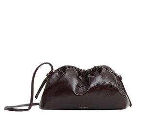 The Mansur Gavriel Mini Cloud Clutch is a small, dark brown lamb leather bag handcrafted in Italy, featuring a gathered top and thin shoulder strap.