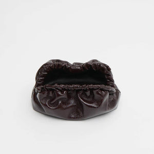The Mansur Gavriel Mini Cloud Clutch is a small, dark brown Italian leather bag with a ruched opening and removable strap, shown against a plain white background.