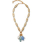 The Marilla Necklace by Lizzie Fortunato features tan oval beads, a gold chain extender, and five assorted blue, white, and gold charms for an ocean-inspired touch.