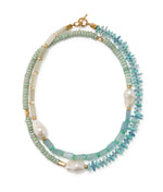 The Cabana Necklace by Lizzie Fortunato features double strands with light green and turquoise beads, irregular white pearls, gold accents, and a gold clasp.