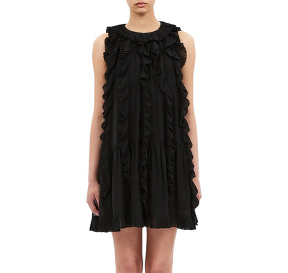 A woman wearing the Ulla Johnson Signe Mini Dress, a sleeveless silk style with cascading ruffles, stands against a white background.