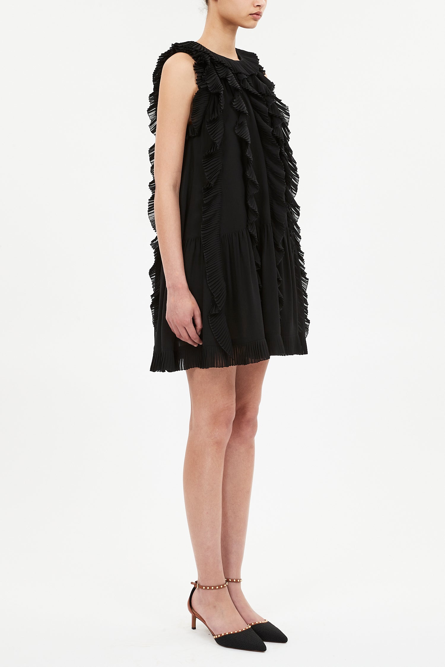 A person wearing the Ulla Johnson Signe Mini Dress and black pointed-toe heels with ankle straps, standing against a plain white background.