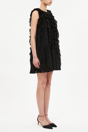 A person wearing the Ulla Johnson Signe Mini Dress and black pointed-toe heels with ankle straps, standing against a plain white background.