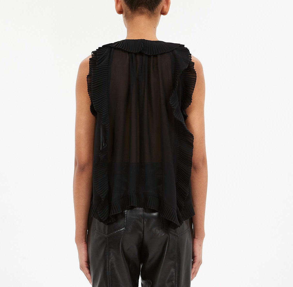 A model is shown from the back wearing the Ulla Johnson Sabra Cascading Ruffle Top—a sleeveless, sheer black pleated top with subtle ruffles—paired with black leather pants against a plain white background.