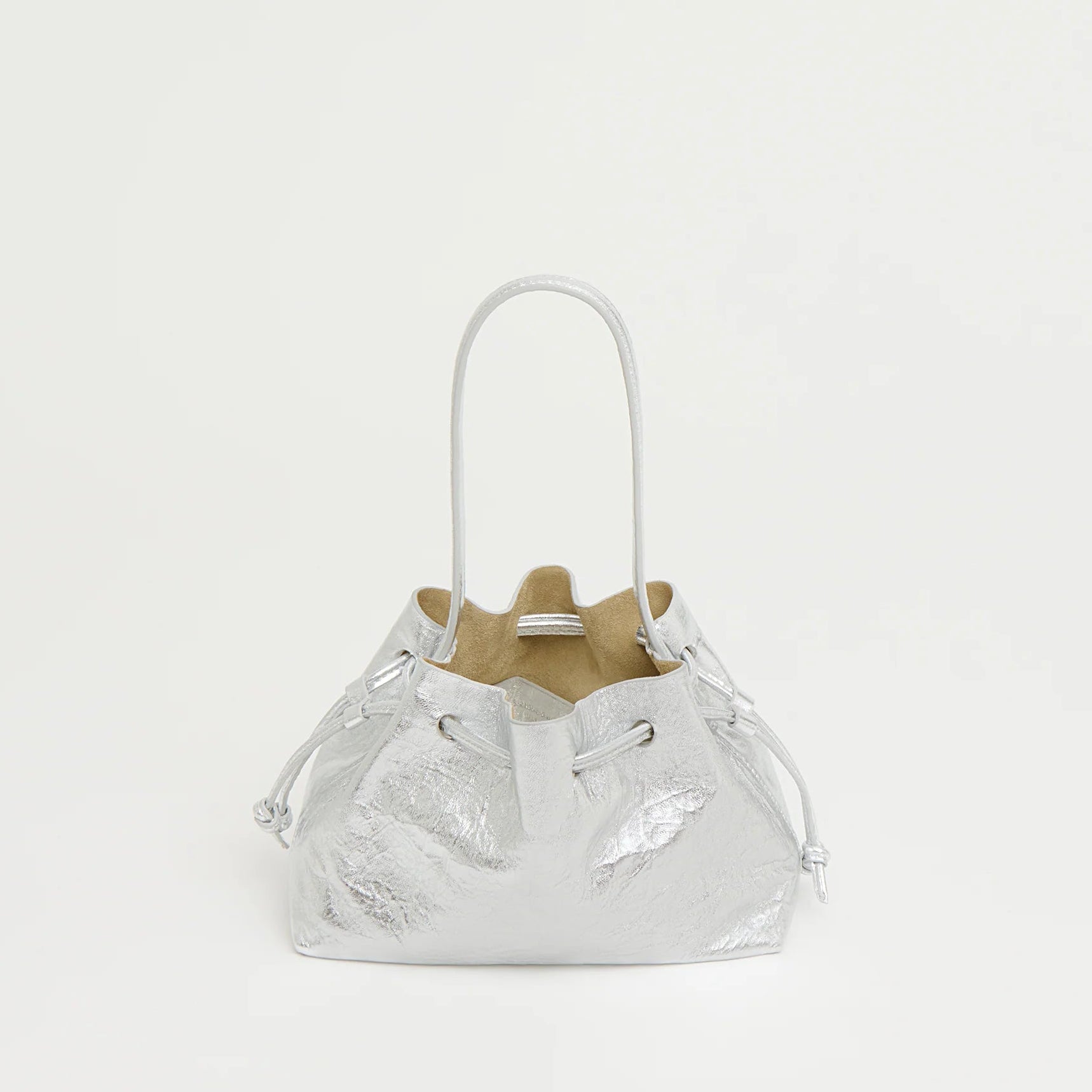 The Mansur Gavriel Drawstring Crinkle Pouchette is a small silver metallic bucket bag made from premium leather with thin handles, shown against a plain white background.