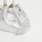 The Mansur Gavriel Drawstring Crinkle Pouchette is a metallic silver handbag with a textured finish and two handles, displayed against a plain white background.