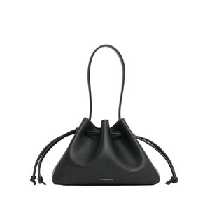 The Mansur Gavriel Drawstring Pouchette is a black compact Italian leather handbag with two top handles, side knots, and minimal gold branding at the bottom—ideal for carrying your essentials.