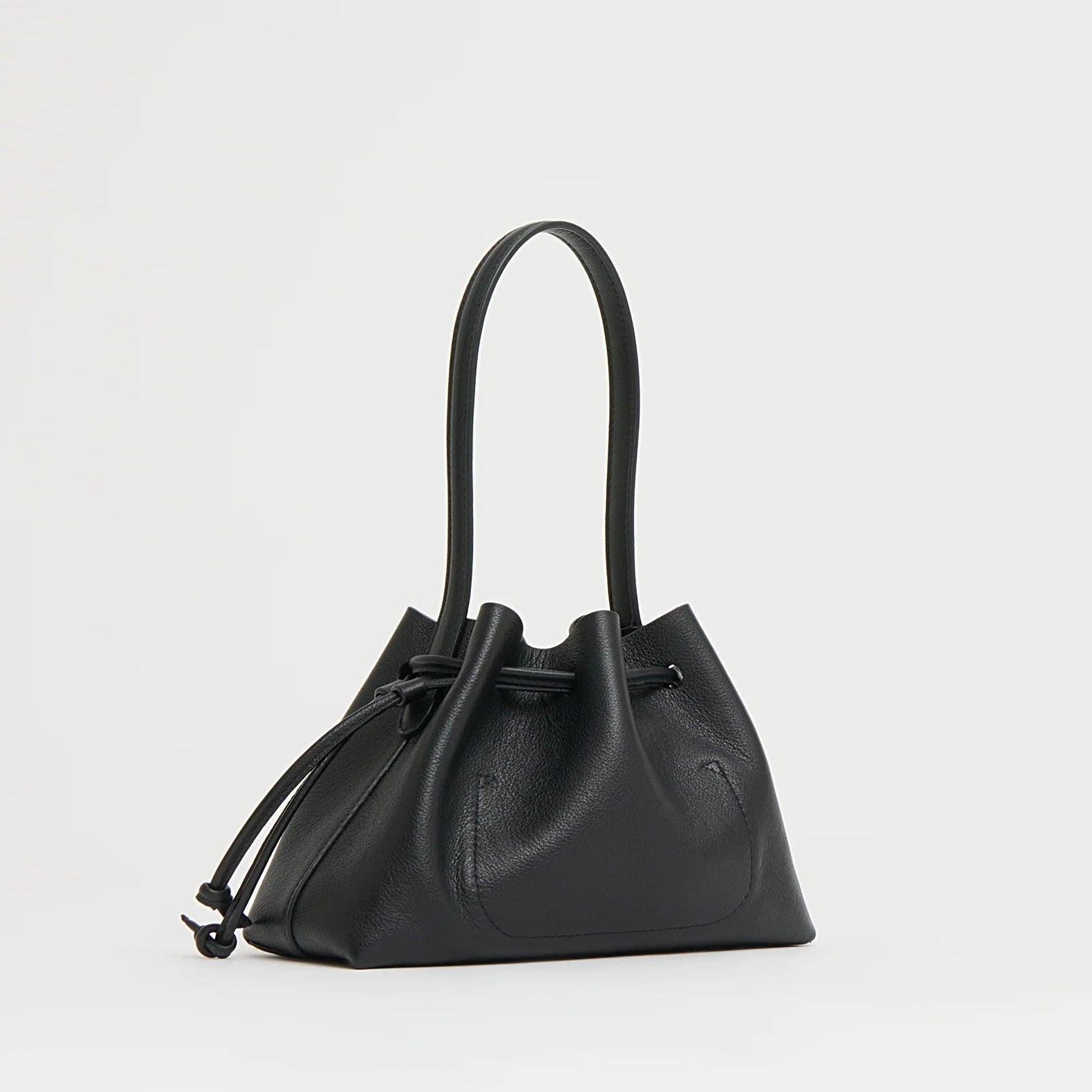 The Mansur Gavriel Drawstring Pouchette is a compact black handbag crafted from Italian leather, featuring a curved top handle—ideal for carrying your essentials in style. Displayed against a plain white background.