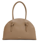 The Fortuna Bowling Bag by Mansur Gavriel features taupe Italian leather, a rounded top, two handles, knotted strap details, and a gold embossed logo near the base.